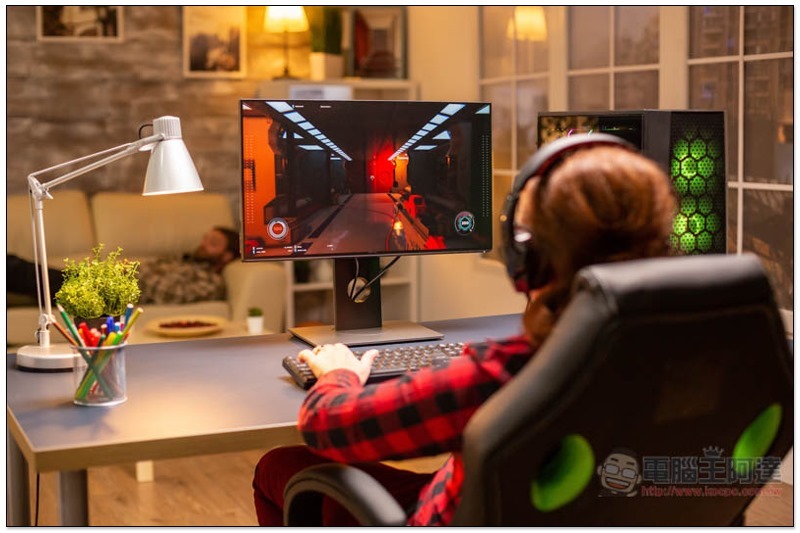 Back view of female gamer playing on powerful computer PC late at night in the living room