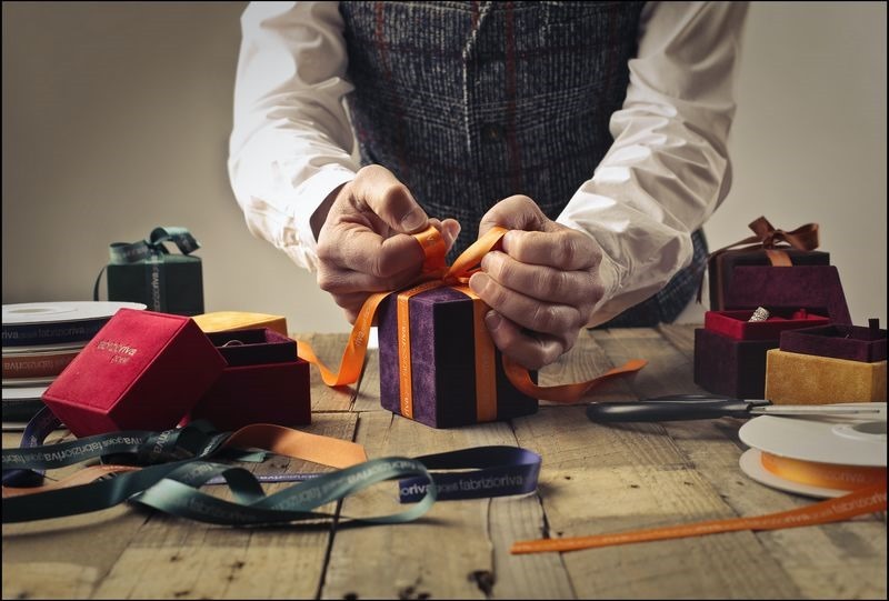 person-tying-ribbon-on-purple-gift-box-1050256